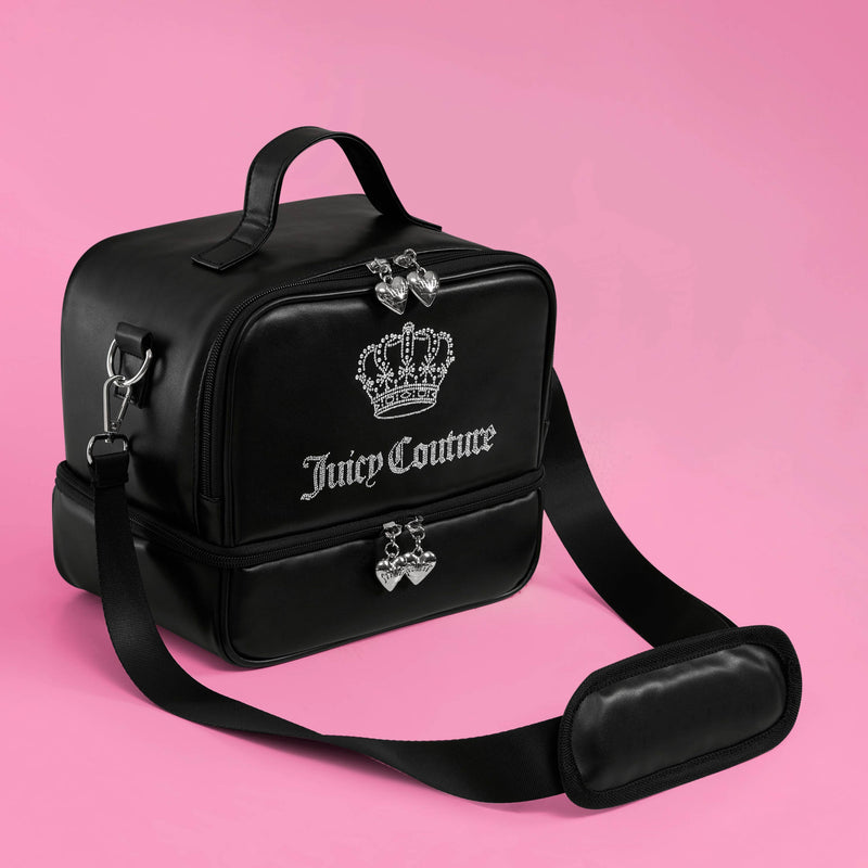 A black Double Zip Chill Cooler Bag from Juicy Couture, featuring a crown logo, silver zippers with heart charms, and an adjustable shoulder strap, sits on a pink background.