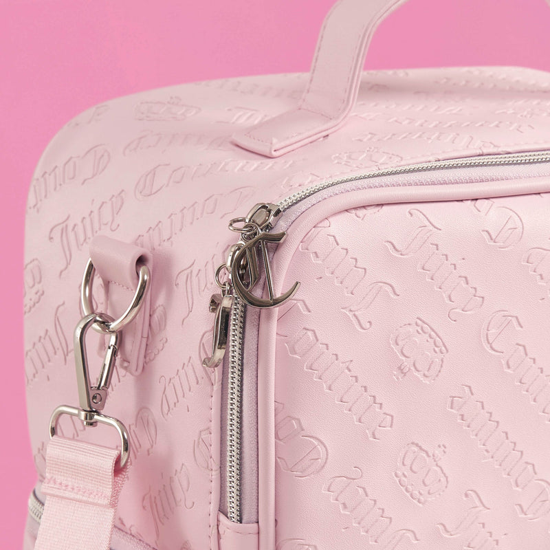 A close-up of a light pink Double Zip Chill Cooler Bag by Juicy Couture, featuring embossed lettering, silver zippers, and hardware, set against a pink background.