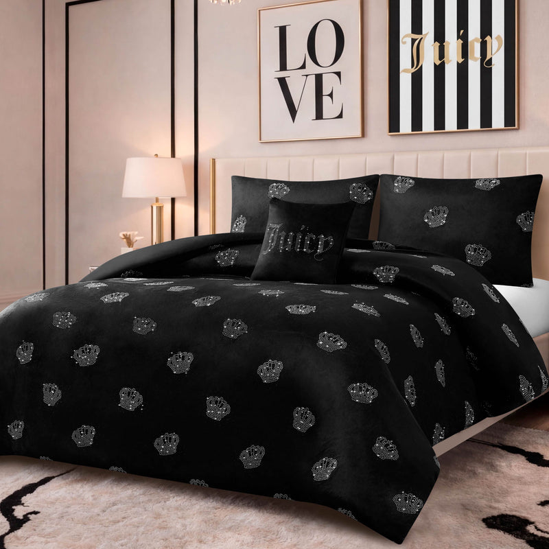 A bedroom with a black Velvet Rhinestone Royal Bling Comforter Set featuring crown patterns, a matching Juicy pillow, beige walls, a lamp, and framed wall art reading LOVE and Juicy.