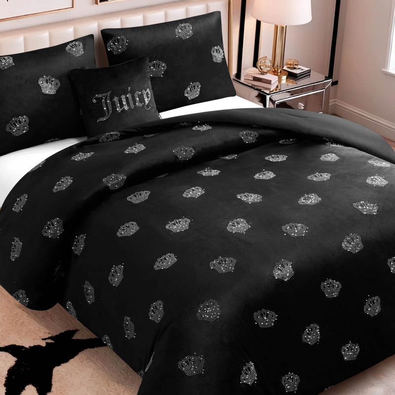 The Velvet Rhinestone Royal Bling Comforter Set features a luxurious black velvet bedding adorned with sparkling silver rhinestone crown patterns and is paired with a coordinating Juicy pillow. Complemented by a bedside table with a lamp, along with neutral-toned walls and flooring, this set creates an elegant and chic atmosphere. The Velvet Rhinestone Royal Bling Comforter Set brings sophisticated glamour to any fashionable bedroom.