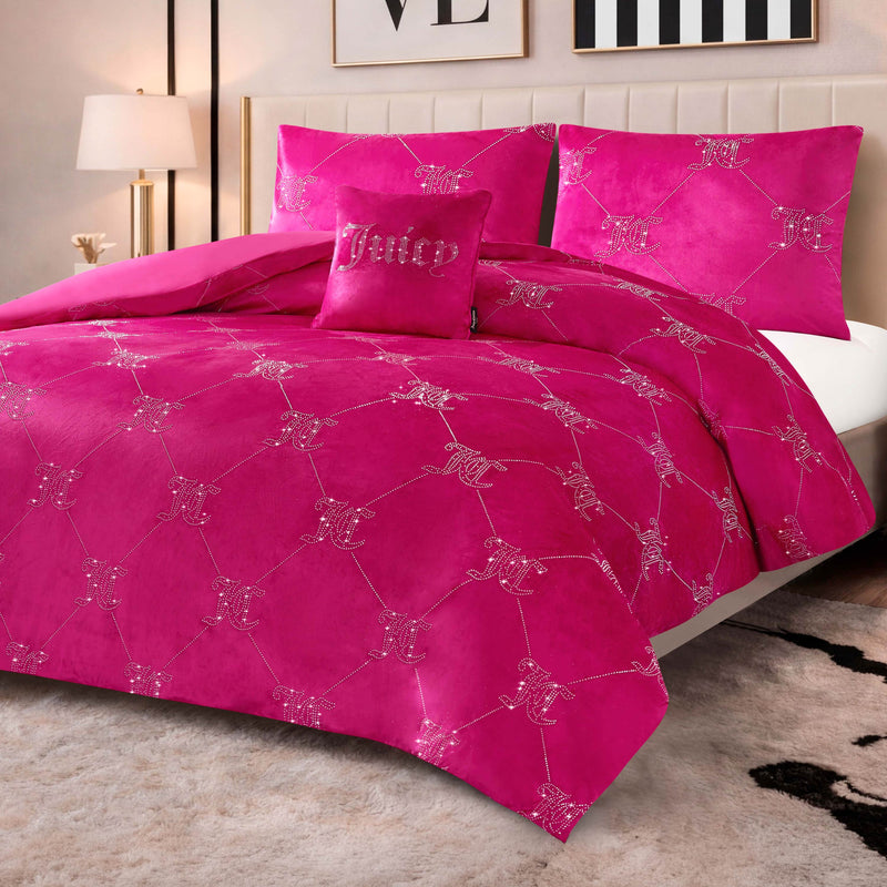 A bed with the Velvet Rhinestone Logo Link Bling Comforter Set—featuring plush velour bedding and sparkling rhinestone logo accents—sits in a modern room alongside a lamp, wall art, and a patterned rug.