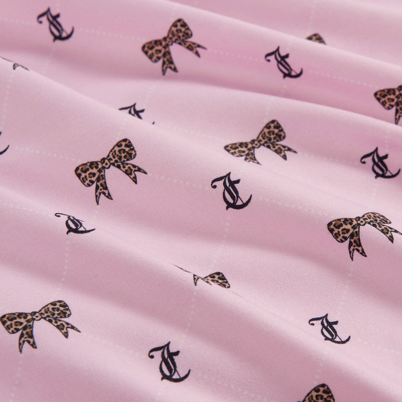 Light pink Printed Microfiber Sheet Set featuring a repeating pattern of leopard-print bows and black anchor symbols—reminiscent of playful Juicy Couture designs. The fabric is slightly gathered, creating soft folds and gentle shadows, making it an ideal choice for adding a touch of luxury bedding style to your room.