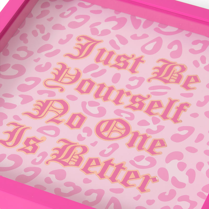 A pink-framed Shadow Box Wall Art, 14″ x 14″, featuring a pink leopard print background and gold gothic text that reads “Just Be Yourself No One Is Better.” This Juicy Couture wall art seamlessly blends fashion-inspired design with bold statement style, making it the ideal decorative piece for any trendy space.