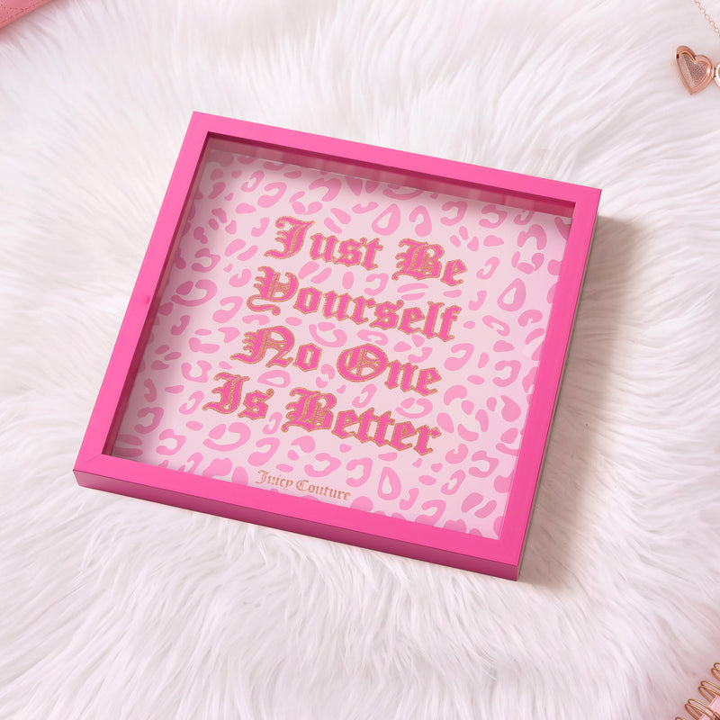 A pink-framed Shadow Box Wall Art (14″ x 14″) features the phrase “Just Be Yourself No One Is Better” in gold lettering on a pink leopard print background over white fur, with the Juicy Couture brand name at the bottom. This fashion-inspired piece captures bold style and confidence, making it a perfect accent for any chic space.