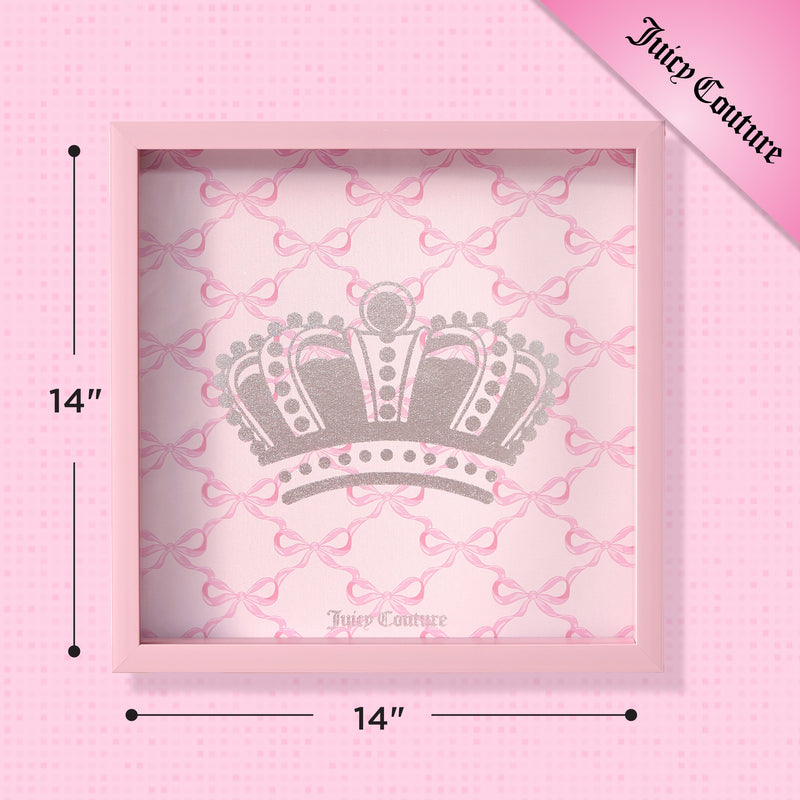The Shadow Box Wall Art, 14″ x 14″, showcases a pink frame and features a large silver crown set against a pink bow-patterned background. The Juicy Couture logo appears in the top right corner, making this fashion-inspired piece an eye-catching addition to any room and perfect for adding chic style as stylish shadow box art.