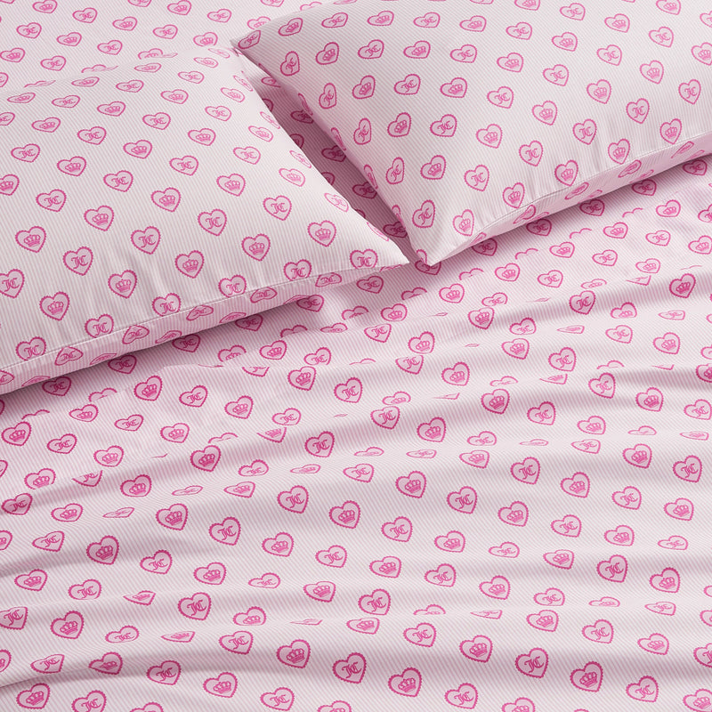 Two pillows and a flat sheet from this Printed Microfiber Sheet Set, featuring a pink heart and crown pattern on a white striped background.