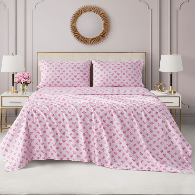 A made bed covered in a Printed Microfiber Sheet Set featuring a repeating pattern of dark pink hearts.