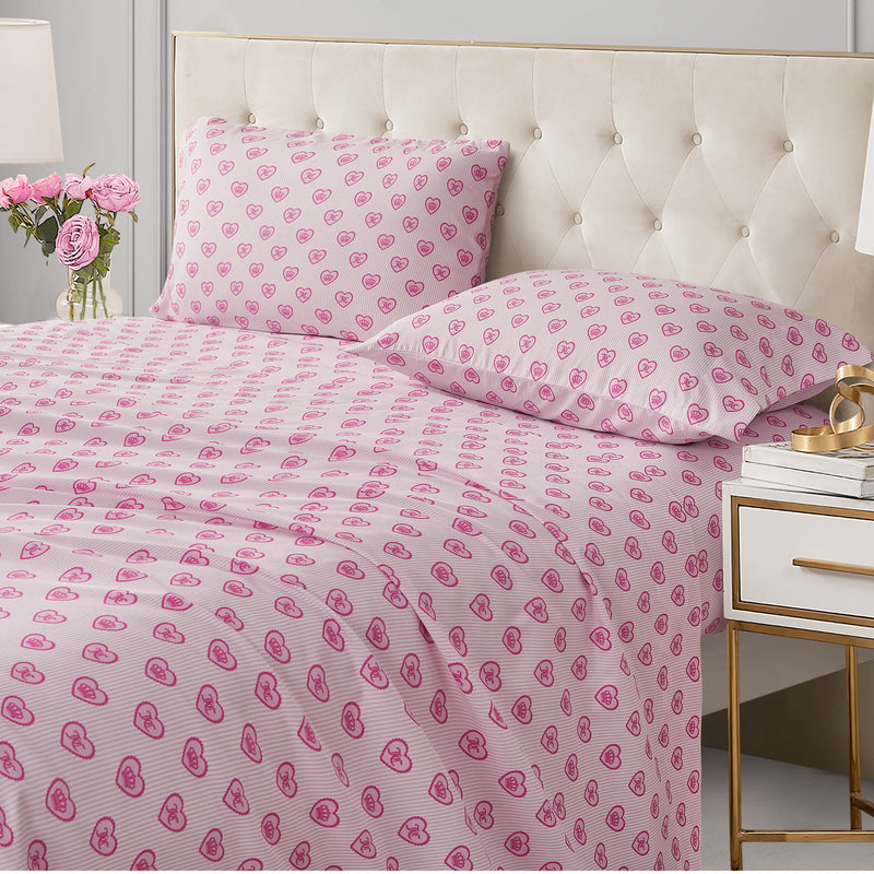 Printed Microfiber Sheet Set featuring Juicy Couture bed sheets and pillowcases with a pink-on-white pattern of small hearts and crowns.