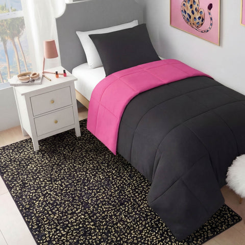 A neatly made twin bed with black and hot pink bedding sits by a white nightstand with drawers. A Metallic Leopard Plush Rug, 4' x 6', covers the floor, while colorful artwork brightens the pale wall.