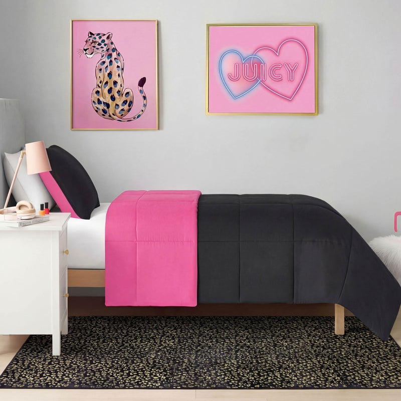 A neatly made bed with black and bright pink bedding sits against a light gray wall. Above hang two framed prints: a colorful leopard, and "JUICY" in pink hearts. Beside the nightstand, the Metallic Leopard Plush Rug (4' x 6') adds a glam flair.