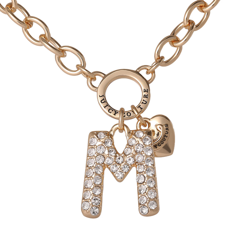 The Bubble Initial Necklace, Letter M, features a gold chain with a sparkling rhinestone-studded letter M pendant and a small heart charm, both hanging from a circular clasp engraved with Juicy Couture—making this Y2K-inspired necklace a perfect blend of iconic style and personalized flair.