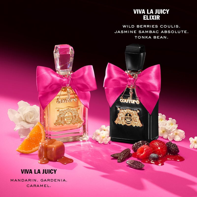 Two Juicy Couture perfume bottles from the Viva La Juicy 3 Piece Fragrance Gift Set, each adorned with pink bows, are artfully arranged among caramel, mandarin slices, berries, and flowers. Text highlights the scents and notes of this luxurious set—featuring Viva La Juicy and Viva La Juicy Elixir—against a pink background.