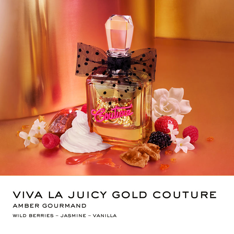 A jeweled perfume bottle adorned with a polka dot bow rests amidst wild berries, vanilla, white flowers, caramel, and cream on a golden and peach backdrop. This luxurious Viva La Juicy Gold Couture 3 Piece Fragrance Gift Set is the perfect addition to any women’s gift collection. Text below reads: Viva La Juicy Gold Couture.