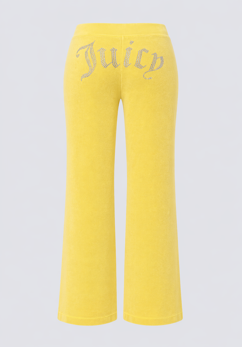 The Big Bling Washed Terry Track Pants are yellow vintage-style velour pants with a flared leg, featuring the Juicy logo in rhinestones across the back and no visible pockets or extra embellishments.