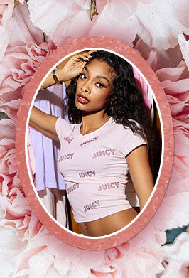 Woman wearing a 'Juicy' t-shirt in front of a pink floral background