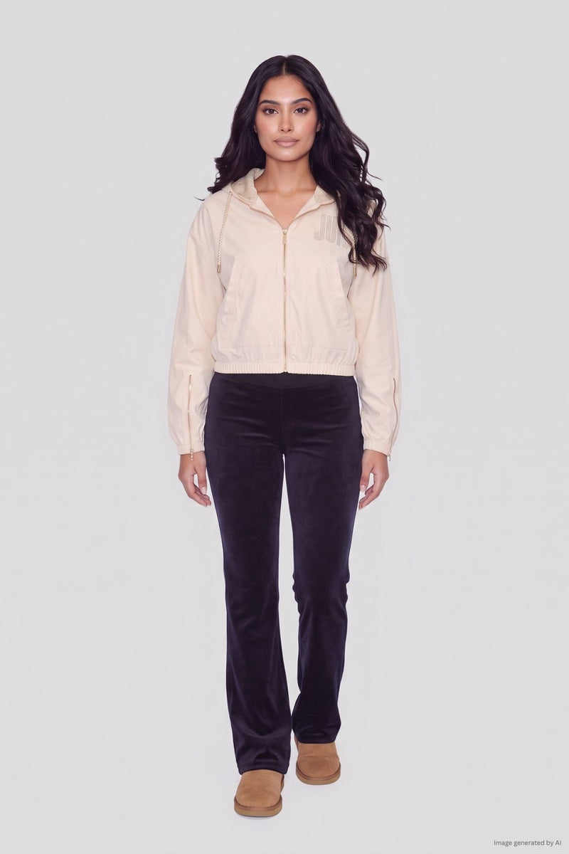 A woman wearing a cream-colored, crystal Juicy logo Statement Jacket, black trousers, and tan ankle boots.