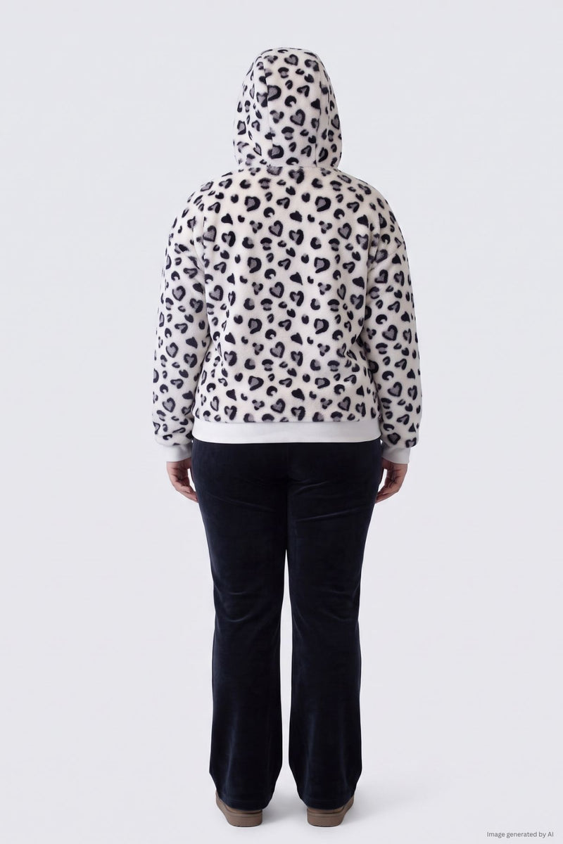 A person seen from behind wearing a Plus-Size Fur Jacket, a plush, hooded white zip-up with a black heart-print pattern, paired with dark trousers.