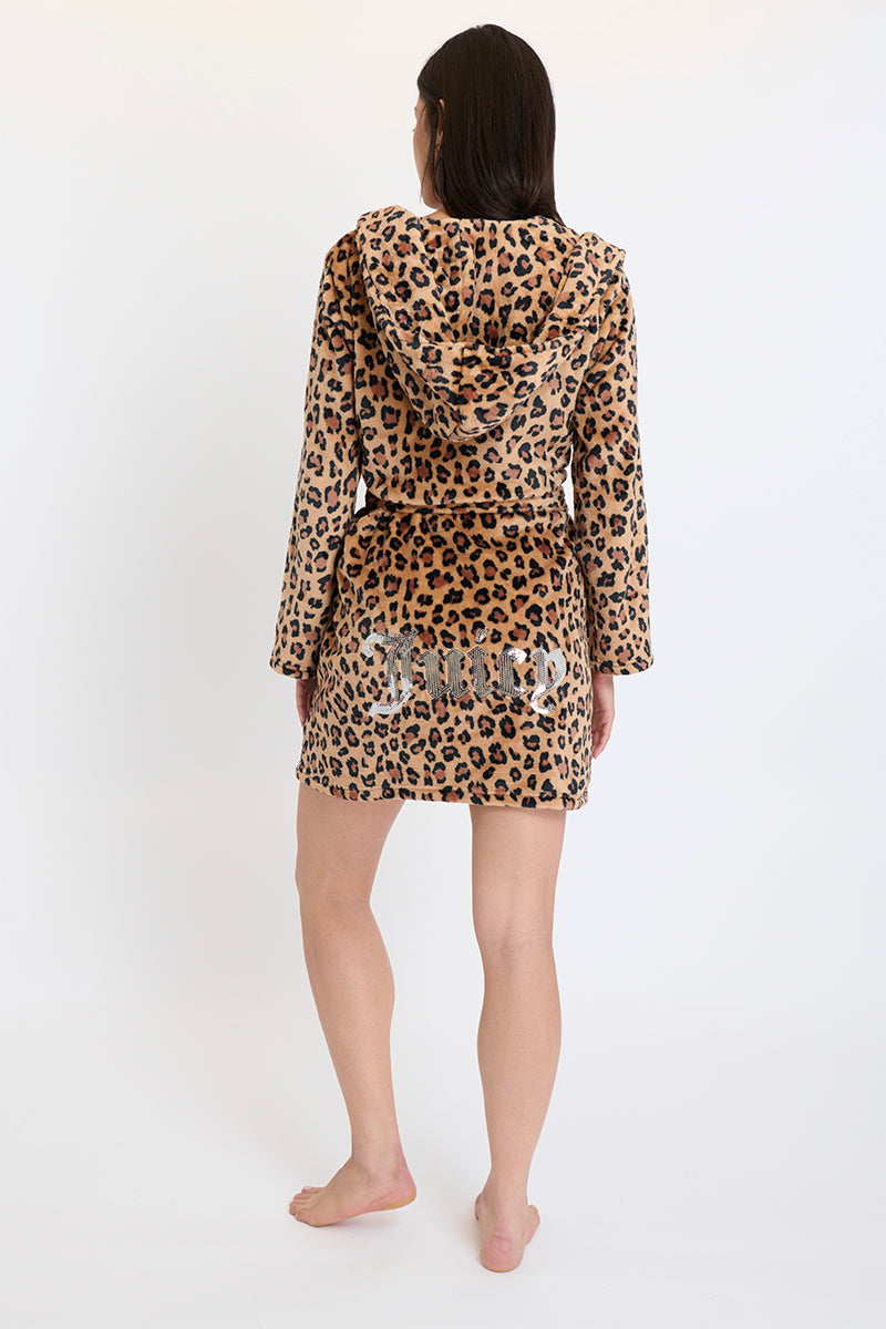 A woman stands barefoot, facing away, wrapped in a brown and black leopard print Hooded Luxe Plush Robe, set against a plain white background.