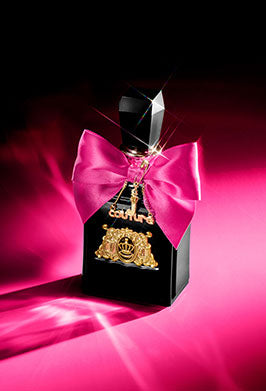 Black perfume bottle with hot pink bow on a pink background
