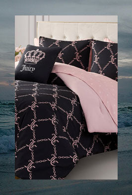 Bedding set with black pattern and pink blanket on a bed against a dark ocean background