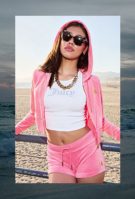 Woman in pink tracksuit and sunglasses on a beach framed in an image of a dark beach