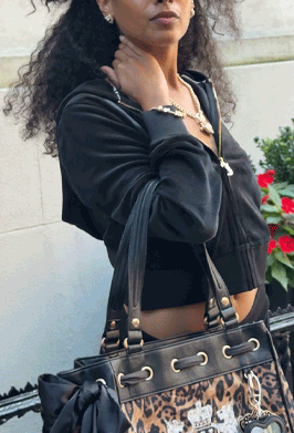 GIF of woman in black Juicy Couture tracksuit holding a black leather and gold detailed Juicy Couture branded bag with a cheetah print.