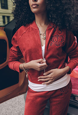 Woman in red tracksuit with crown logo detailing stepping outside of taxi.