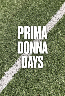 A square graphic with the text 'PRIMA DONNA DAYS' in large white block letters over a green grass field divided diagonally by a white line.