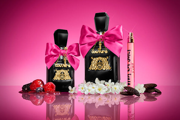 Two black perfume bottles with hot pink bows on a gradient pink background