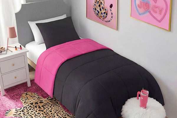 Bedroom with pink and black bedding, nightstand, and wall art.