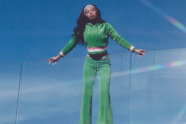 Person in green tracksuit standing outside against blue sky