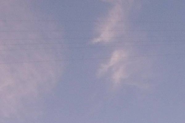Partial view of a blue sky with a power line and some clouds.