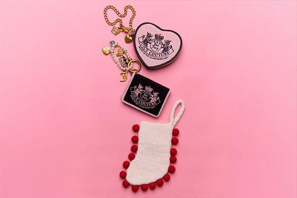 Heart-shaped wallet and black rectangular Juicy Couture wallet on a pink background