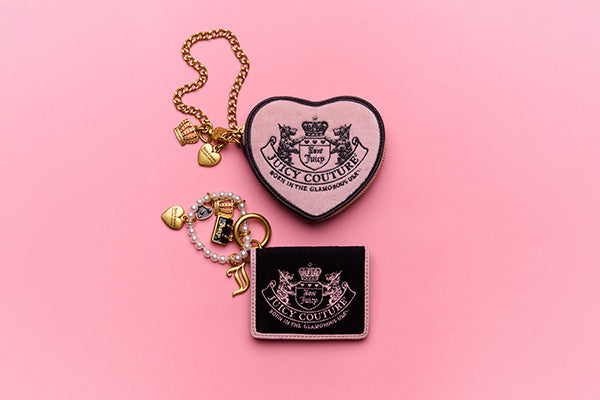 Heart-shaped Juicy Couture wallet and rectangular Juicy Couture wallet on a pink background