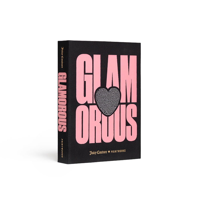 Introducing the Juicy Couture x Printworks Jewelry Box: This black book-shaped box features bold pink text reading “GLAMOROUS” in two lines, with a sparkly heart replacing the letter O. The spine also displays “GLAMOROUS,” while “Juicy Couture x Printworks” is printed at the bottom. Perfect for stylishly storing your jewelry, this clever design doubles as both a book and a chic jewelry box.