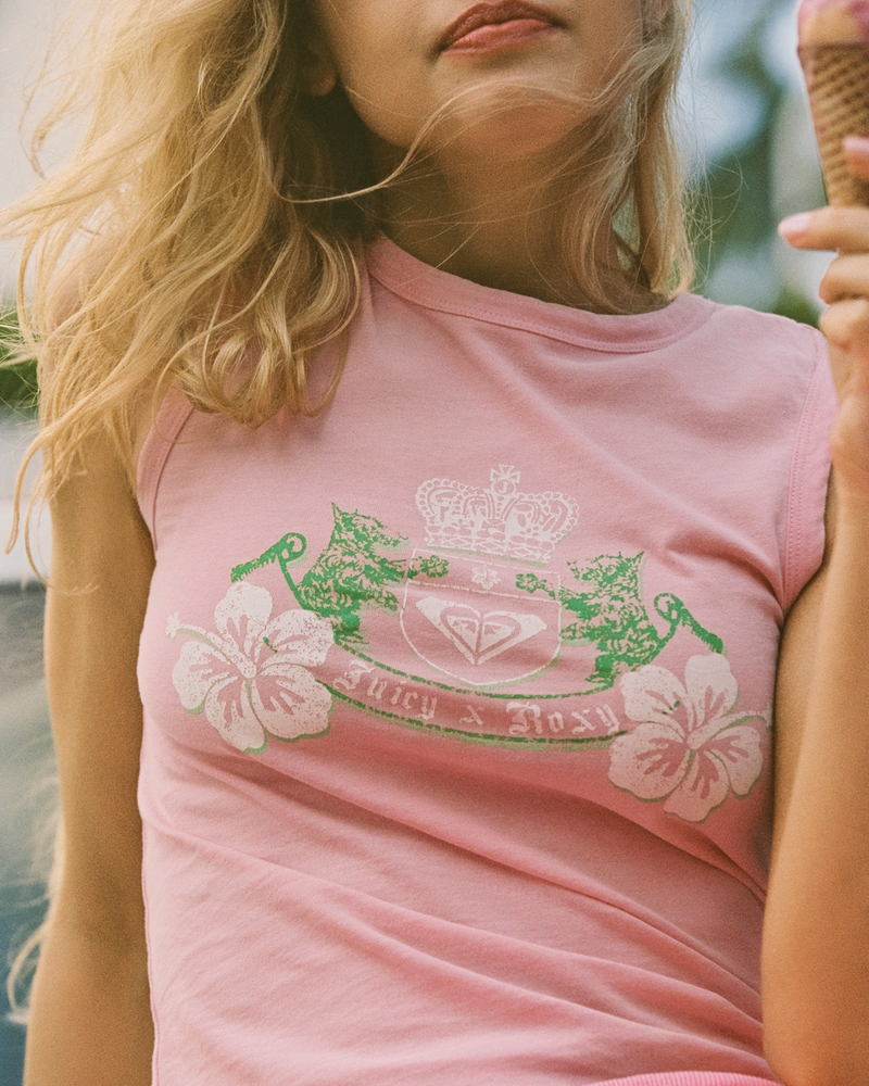 A woman with long blonde hair wears the Roxy x Juicy Crest Tank Top, featuring floral and crown designs. She is outdoors holding an ice cream cone, her face partially out of frame.