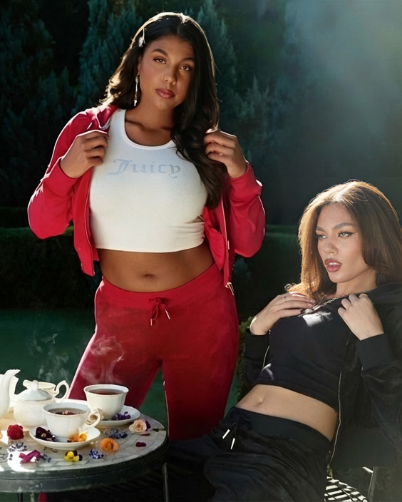 Two women in a garden in Juicy tracksuits surrounded, sitting at a table with tea served surrounded by flowers