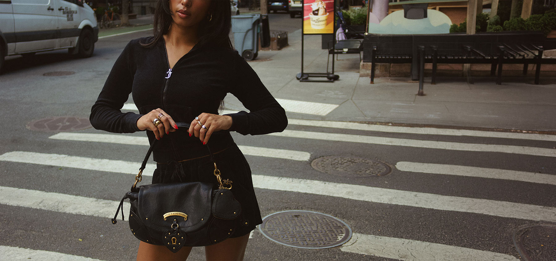Person in black tracksuit holding a black bag standing in a city street