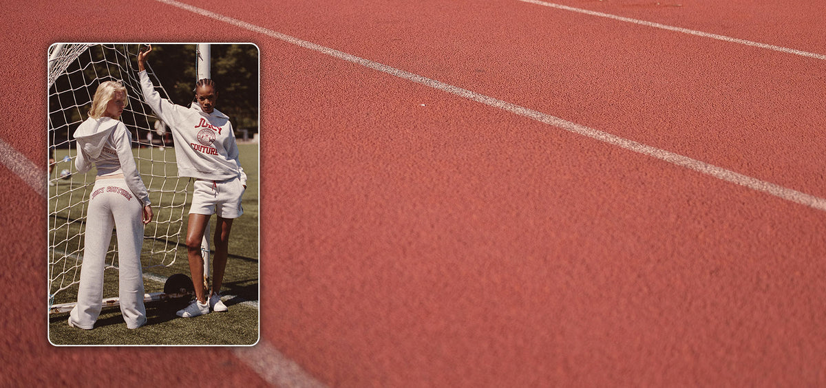 A model wears a matching white athletic tracksuit with red lettering, standing on a red running track next to a soccer goal. A small inset in the top-left corner shows the back view of the model wearing the white sweatpants and top.