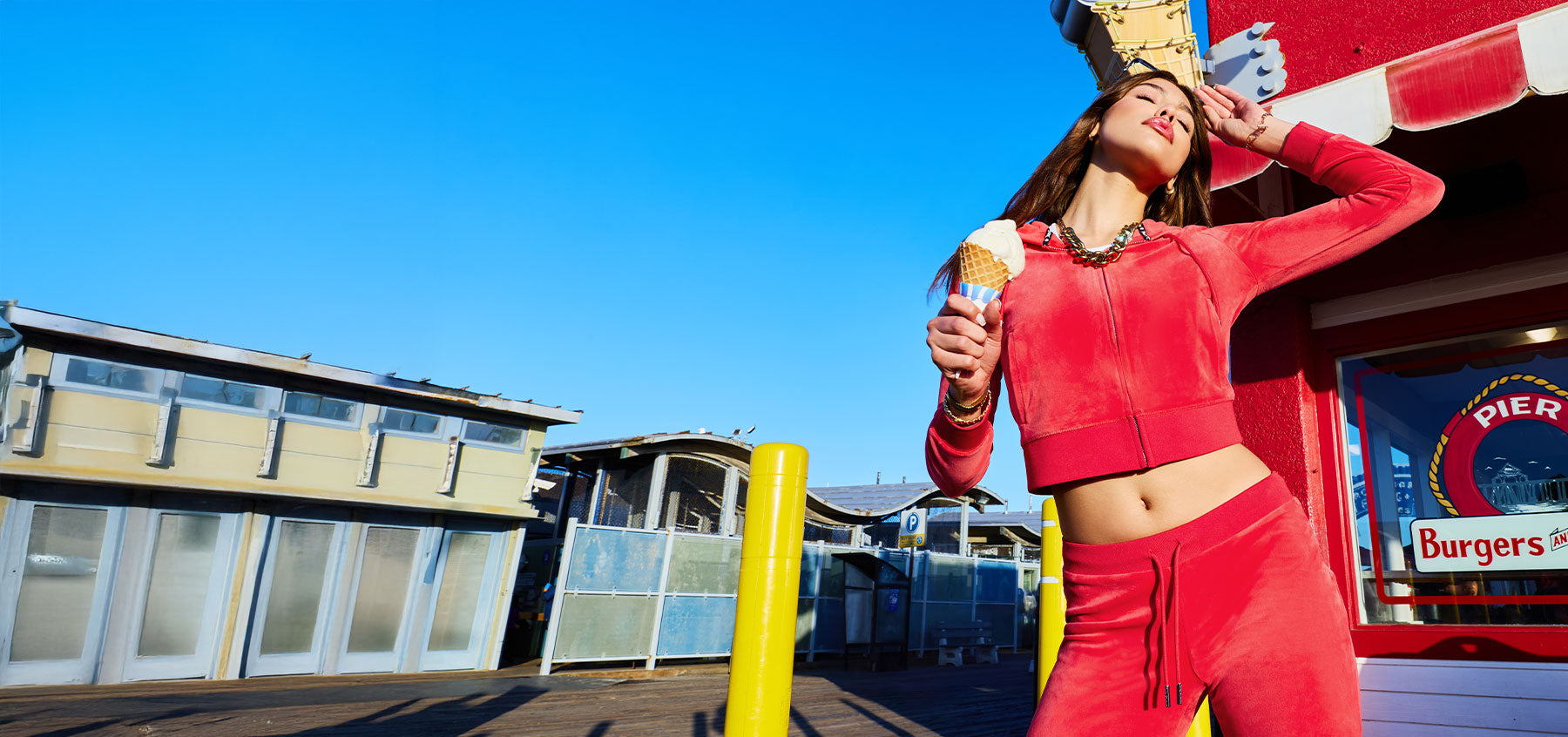 Woman in a red tracksuit holding an ice cream cone in front of a fast food restaurant.