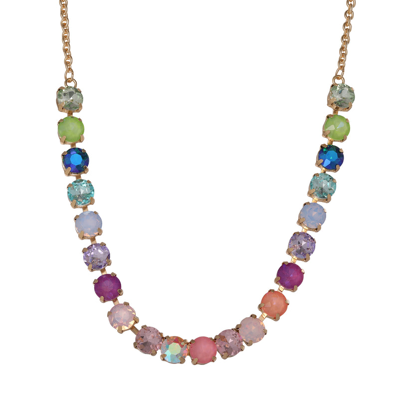 The Tennis Necklace with Multicolor Crystals is a gold-plated statement piece featuring round, vibrant crystals arranged in a symmetrical pattern along the front.