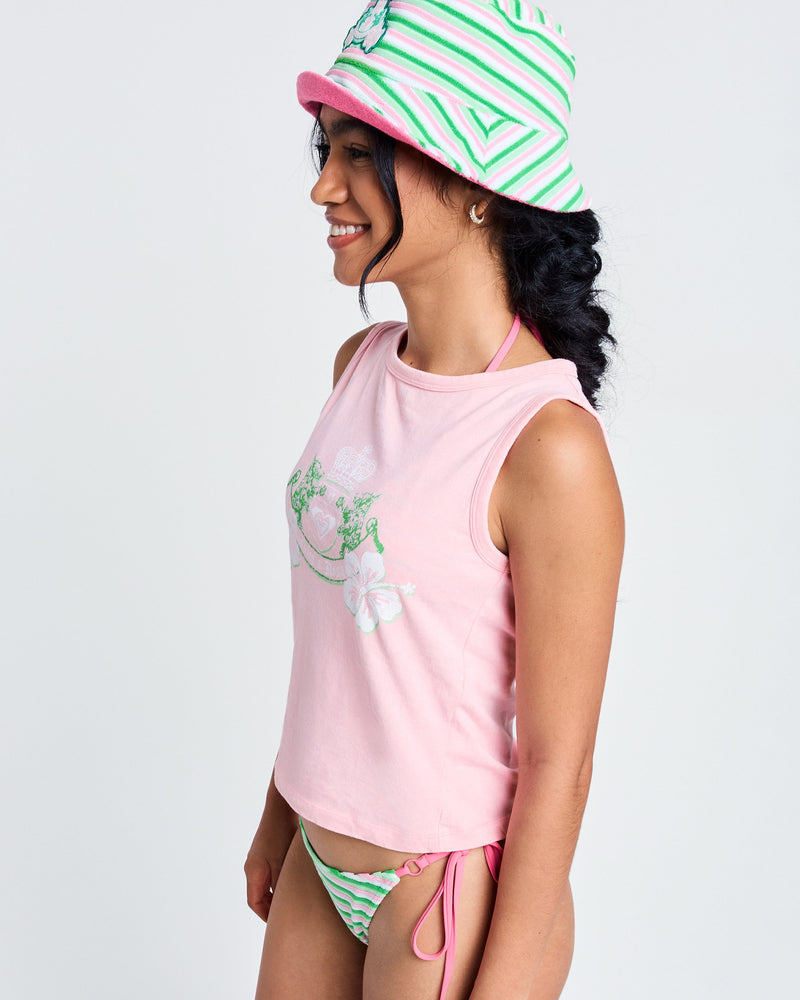 A woman in a Candy Pink Roxy x Juicy Crest Tank Top, a pink and green striped bucket hat, and matching bikini bottoms smiles in profile against a plain white background.