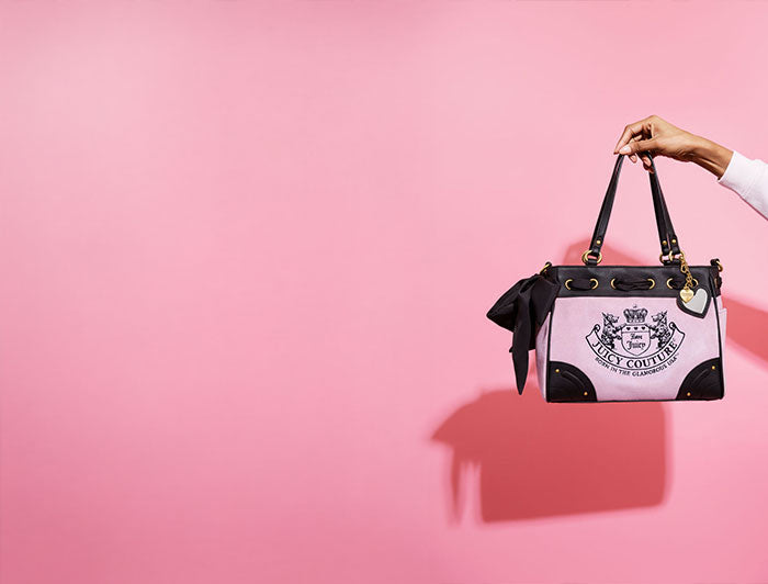 Handbag with a visible brand logo held against a pink background