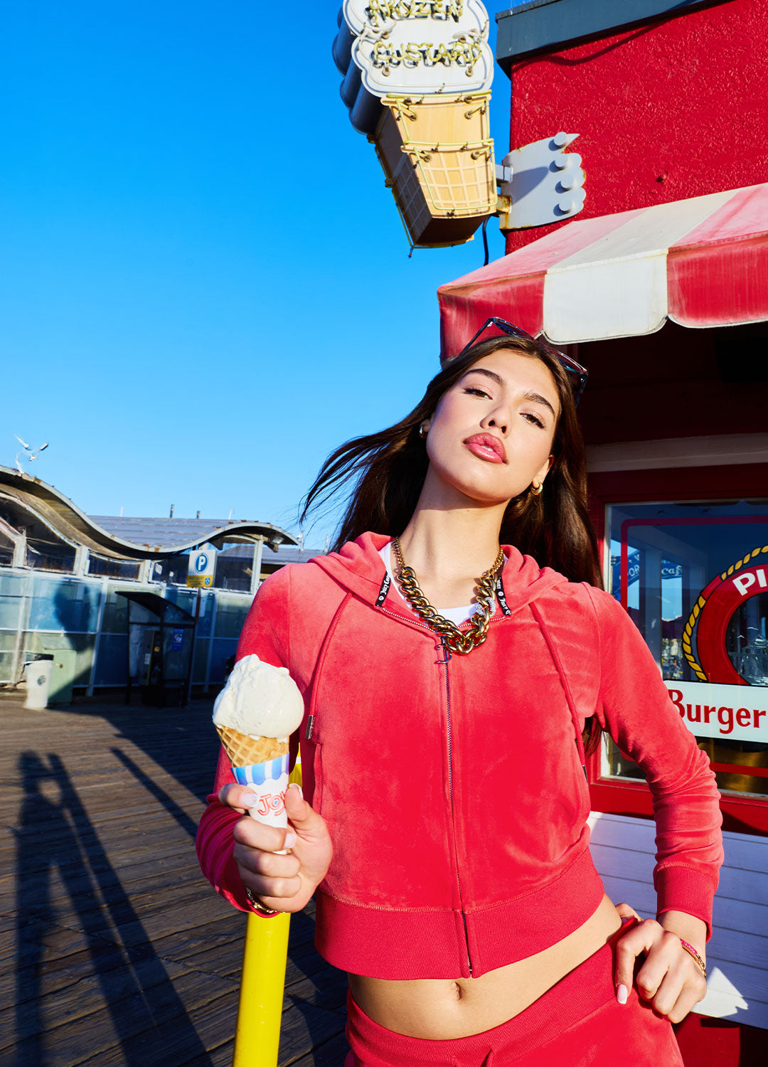Woman in a red tracksuit holding an ice cream cone in front of a fast food restaurant.
