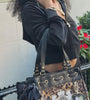 Close up video of a woman in a black Juicy Couture tracksuit holding a tote bag with leather and gold detailing, cheetah print, a black bow, and the Juicy Couture logo.