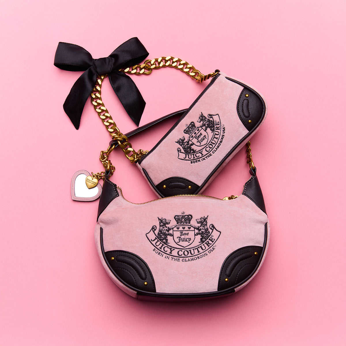 Two pink and black handbags with gold chain and bow on a pink background, featuring the Juicy Couture logo.