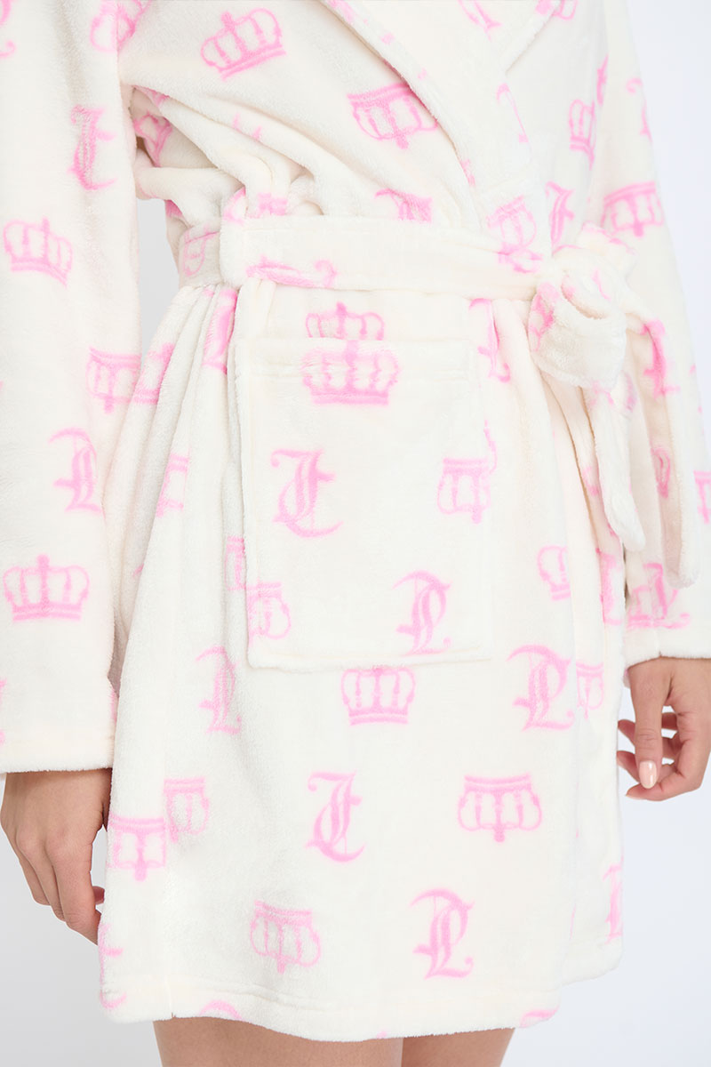 A person wears a Hooded Luxe Plush Robe—white with pink crown and J designs—tied at the waist. The image focuses on the soft robe’s cozy midsection and pocket area.